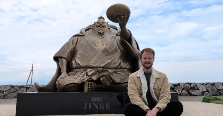 Mann sitzt vor der Jinbei-Statue an der Nagabeta Seabed Road