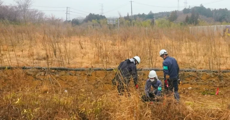 Arbeiter in Schutzuniformen dekontaminieren einen Landstrich nahe dem Atomkraftwerk Fukushima. Februar 2026