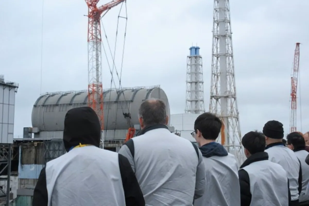 Eine Tourgruppe steht vor Reaktor 3 des Atomkraftwerks Fukushima Daiichi in 2026