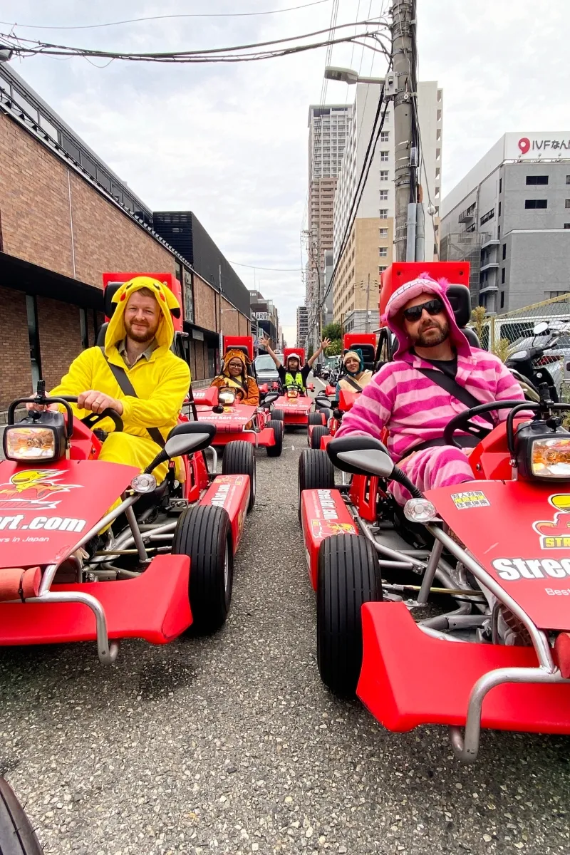 Zwei Männer fahren vorab bei einer Go Kart-Kolonne durch Osaka