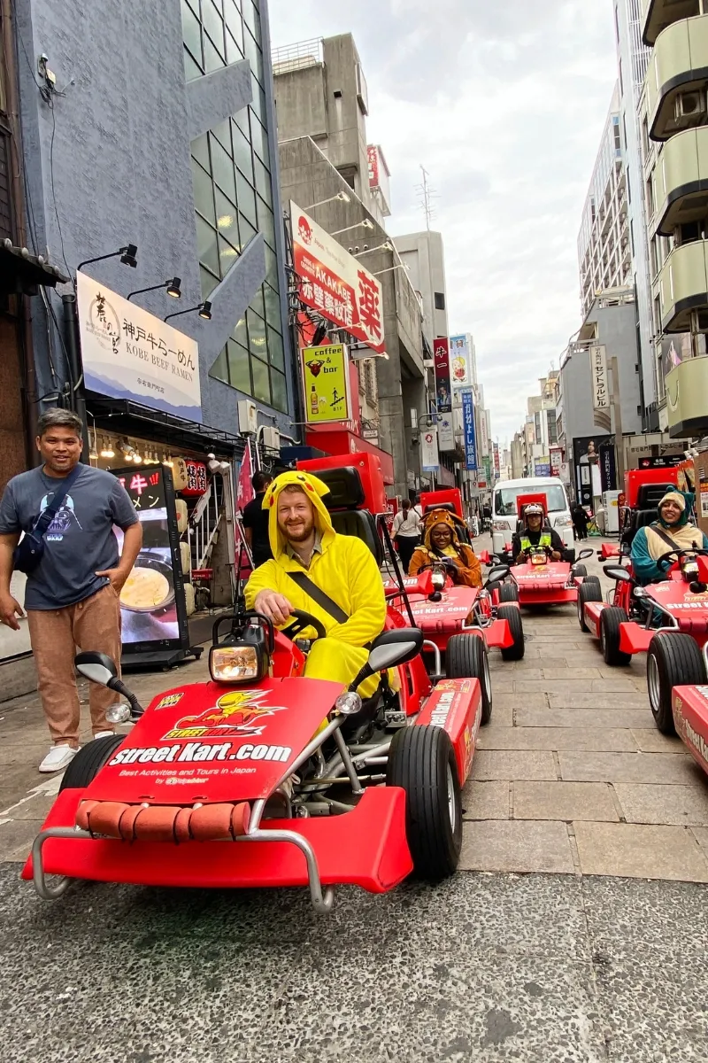 Mann im Pikachu-Kostüm fährt Go Kart durch Dotonbori