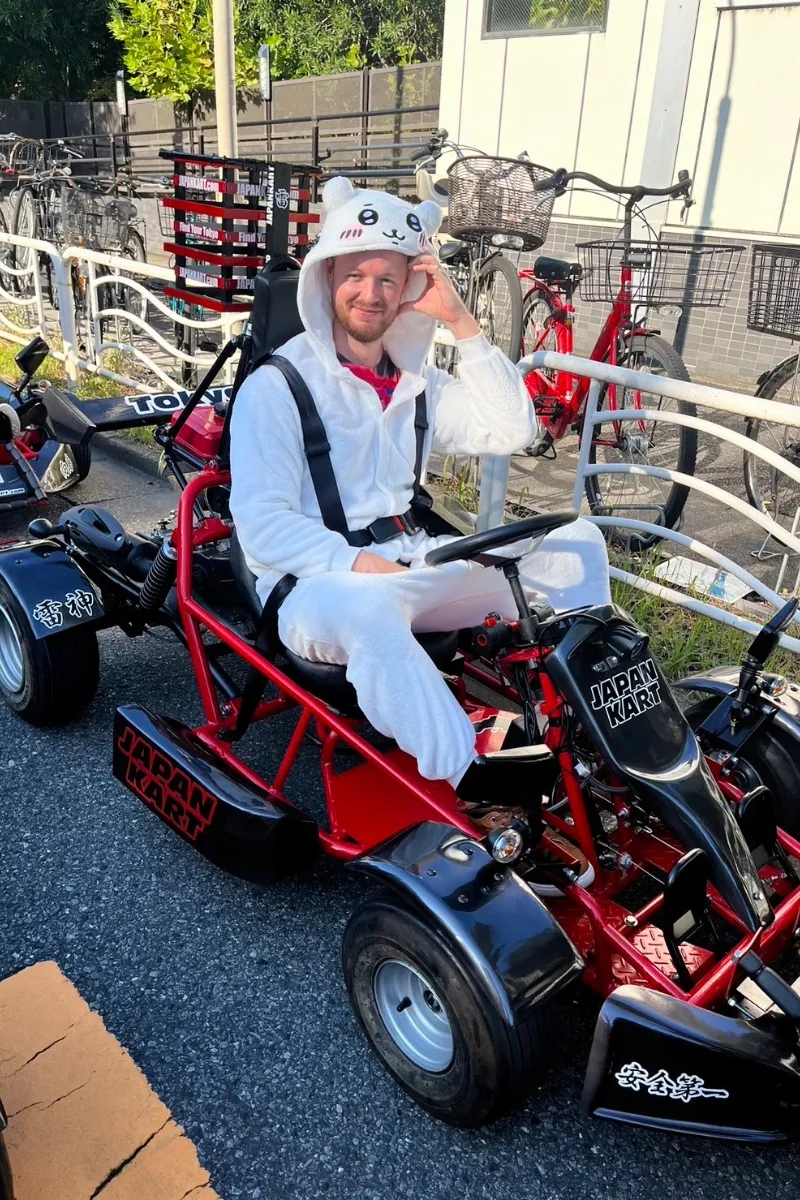 Mann im süßen Animekostüm fährt Go-Kart durch Tokio