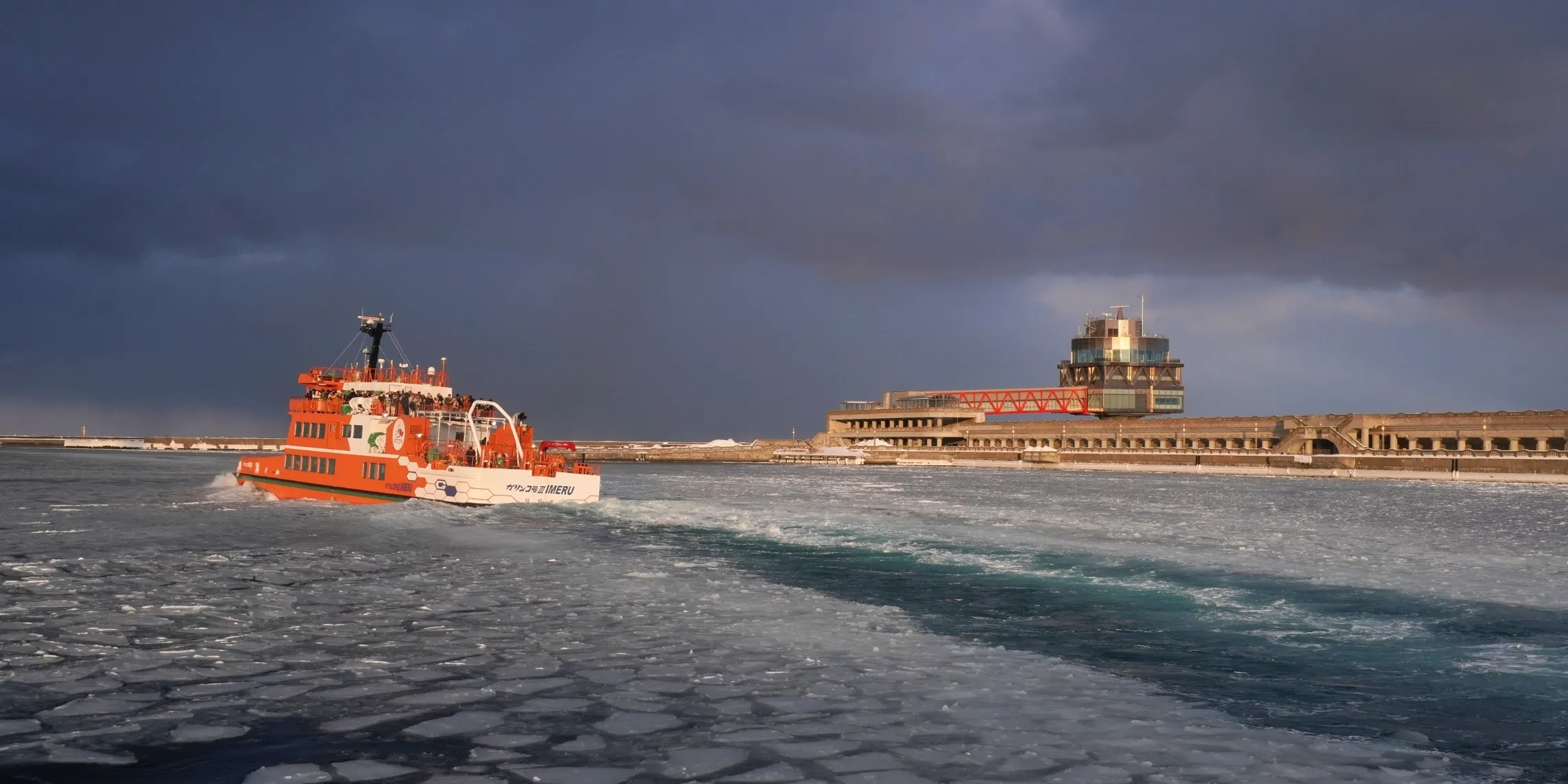 Ein Garinko-Eisbrecher legt in Mombetsu ab, mit dem Okhotsk Sea Tower im Hintergrund