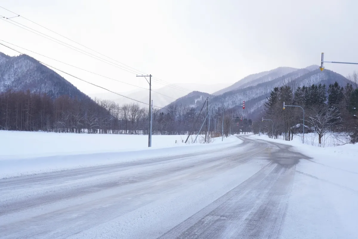 Verlassene Landstraße im winterlichen Hokkaido mit Bergen im Hintergrund