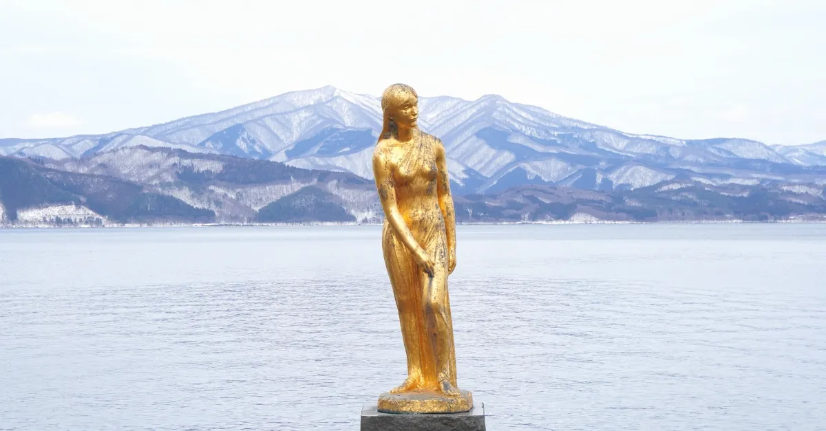 Die Tatsuko-Statue am Tazawa-See, mit dem See im Hintergrund an einem verschneiten Februartag
