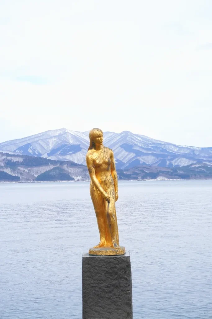 Die Tatsuko-Statue am Tazawa-See, mit dem See im Hintergrund an einem verschneiten Februartag