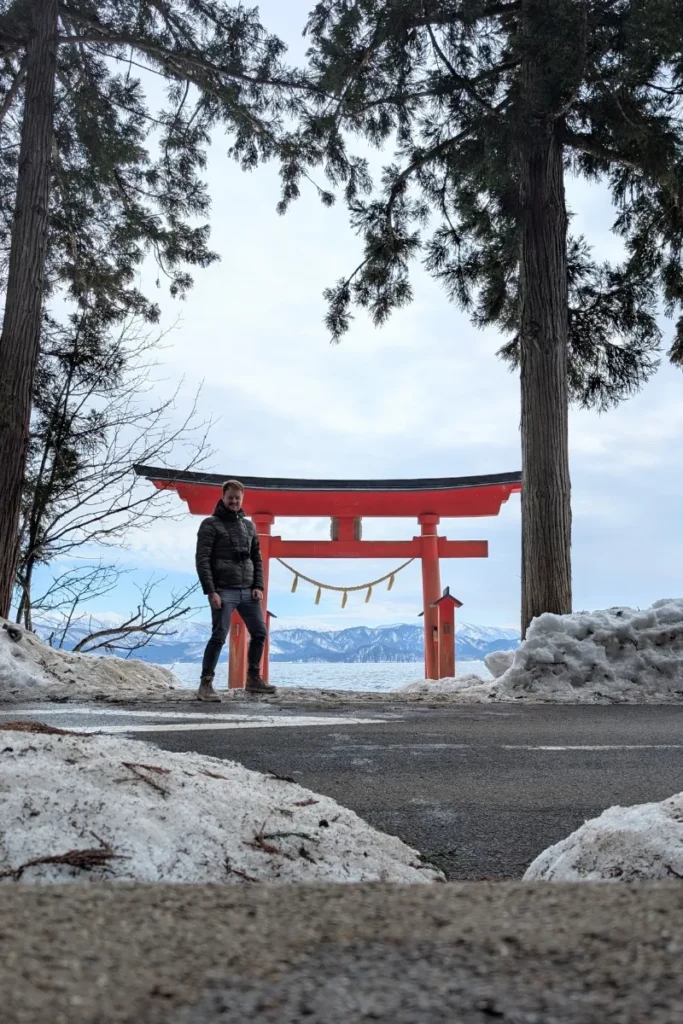 Fabian steht vor dem Torii des Gozanoishi-Schreins am Tazawa-See