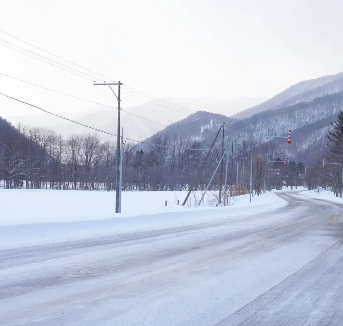 Eine Landstraße inmitten einer Schneelandschaft im ländlichen Hokkaido