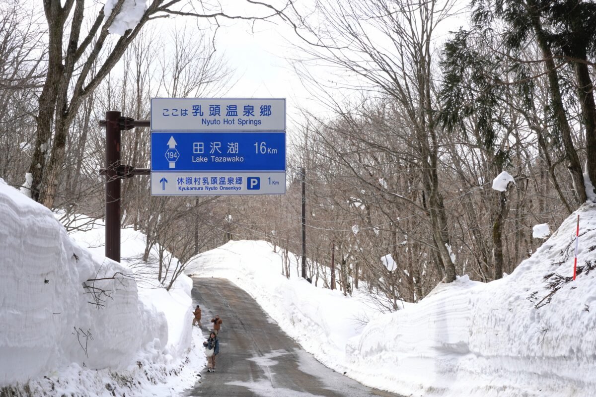 Straßenschild in einer verschneiten Landschaft, welches nach Nyuto Onsen zeigt